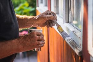 Professional painter repainting wood window trim to prevent dry rot