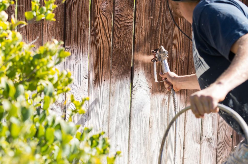 A Grandview Painting employee providing expert fence painting services in Dubuque, IA, showcasing professional tools and skills to ensure top-quality results.