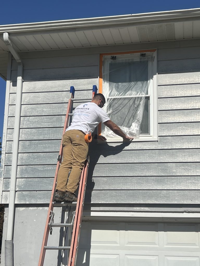 Exterior Painting in Dickeyville - WI in progress as a painter brushes trim along a front porch